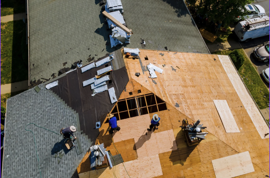 Workers on top of a roof installing shingles